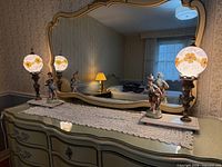 Dresser view showing both matching ceramic figurine lamps illuminated with floral glass globes