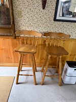 Pair of matching wood bar stools against wall
