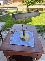 Full view of brass piano lamp on table