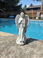 Full view of gray concrete angel statue by pool