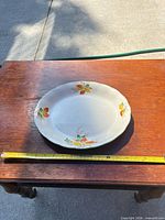 Top view showing full oval platter on table with measuring tape indicating ~13 in length