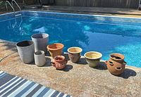 Seven assorted planters lined up poolside showing full group