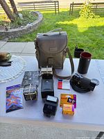 All items laid out: lens, caps, cases, flash, film, bag