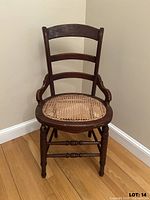 Front view of antique wooden chair, showing caned seat and turned legs