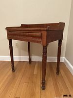 Front view of curly maple writing desk showing gallery and turned legs