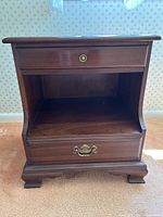 Front view showing top drawer, open shelf, bottom drawer, brass hardware, bracket feet