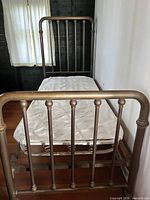 Overall view of assembled brass twin bed frame with bunkie board