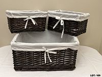 Three dark brown wicker baskets with light grey liners, two small stacked on one large