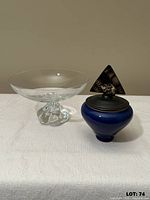 clear glass candy dish and blue covered jar side by side