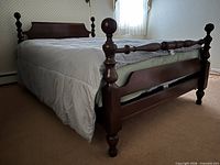 Full view of assembled walnut cannonball queen bed with bedding removed showing footboard, side rails and bunkie board