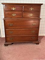 Front view of walnut chest showing seven drawers and brass hardware