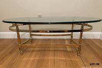 Front view of oval glass coffee table showing glass top and brass frame