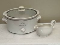 Rival slow cooker assembled with lid beside white gravy boat