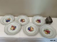 Six bone china plates and silver-rim coasters with holder displayed