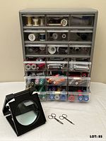 Drawer organizer filled with thread, folding magnifier, two scissors