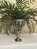 Front view of faux fern in chalice vase