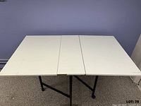 Table fully open showing white laminate top and black legs