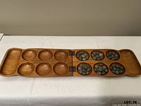 Open wooden Mancala board with seed pieces in pits