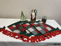 Full lot overview showing placemats, wall hanging, Santa figurine, glass tree, candle