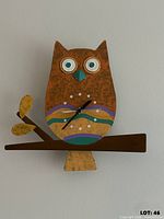 Front view of painted metal owl wall clock on branch