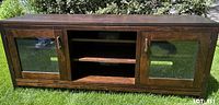 Front view of pine TV stand showing glass doors and open centre