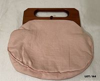 Front view showing wooden handle, latch and pink linen pouch