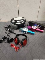 Overall lot showing boombox, two karaoke mics, headphones, headset, power cords