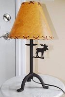 Full view of metal lamp with yellowish-tan lampshade and moose motif on shade and base.