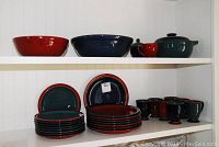 Top shelf shows two large serving bowls (one red interior/blue exterior, one blue glaze) and a tureen with lid plus creamer cup beside it.
