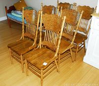 Six matching oak dining chairs grouped on a hardwood floor