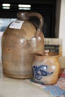 Photo showing both jugs on a table, smaller jug with blue floral design beside larger plain jug