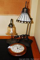Three lamps shown with wall clock on table.