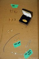 Eight gold jewelry pieces laid out on cardboard with 10K, 14K gold, and 14K white gold labels