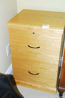 Front view of wooden filing cabinet showing both drawers with black curved handles and lock on top drawer.