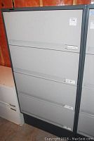 Front view of the closed steel filing cabinet with four drawers and label holders on each drawer.