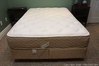 Front view of double mattress and box spring set on metal frame