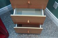 Close-up showing two drawers partially open revealing white interiors and metal side glides.