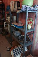 Pair of grey open metal shelving units with various household items placed on them. Shelves are 4-tiered, upright assembled with supports visible.