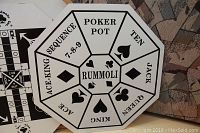 Close-up of the Rummoli interchangeable game board with labeled sections for poker pot, card ranks and sequences.