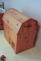 Side view of the custom wooden barn toy box showing its barn-style roof and side details.