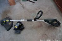 Full view of Yardworks cordless weed trimmer showing shaft, loop handle, trigger handle, and protective guard on the trimmer head.