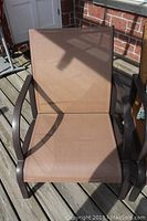 Close-up photo of one chair showing brown mesh fabric seating and curved metal arms.