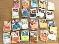 Overview of multiple stacks of assorted Pokémon cards on tabletop