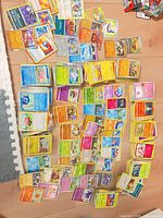 Wide view of multiple stacks and spreads of assorted Pokémon cards on floor