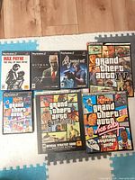 Seven PS2 game cases and strategy guides laid out to show covers