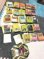 Stacks of loose Pokémon cards and metal tin