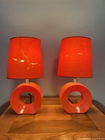 Front view of both orange acrylic base table lamps with shades