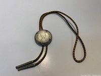 Full bolo tie showing coin slide and braided leather cord