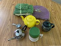 Group view: ceramic teapot, stainless/glass kettle, glass teapot, thermos, infuser, two tea cozies