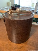 Full view of brown faux leather ice bucket with lid and tongs on top